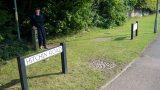 The route heads up the path between these two signs